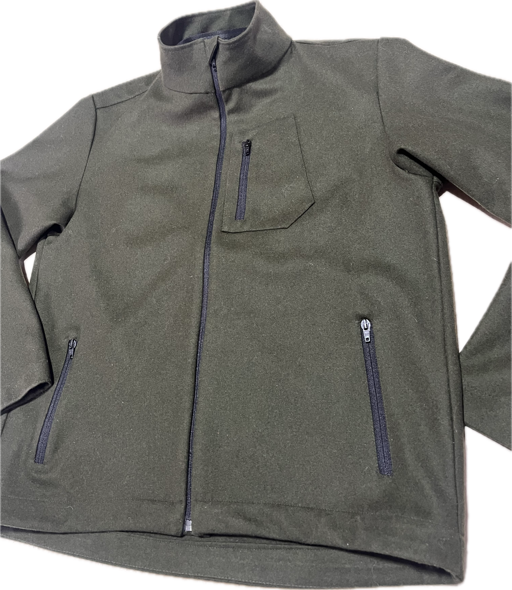Roughstuff Leichtgaist leichte Lodenjacke für Alltag, Wandern und Outdoor-Aktivitäten. Dünne und angenehm zu tragende Jacke aus robuster Wollmischung mit sportlichem Schnitt, verstellbarem Bund und hoher Bewegungsfreiheit durch Rückenfalten. Ausgestattet mit seitlichen Taschen und Brusttasche, ideal als Zwischenschicht oder leichte Außenschicht bei mildem Wetter. Farbe Olivgrün