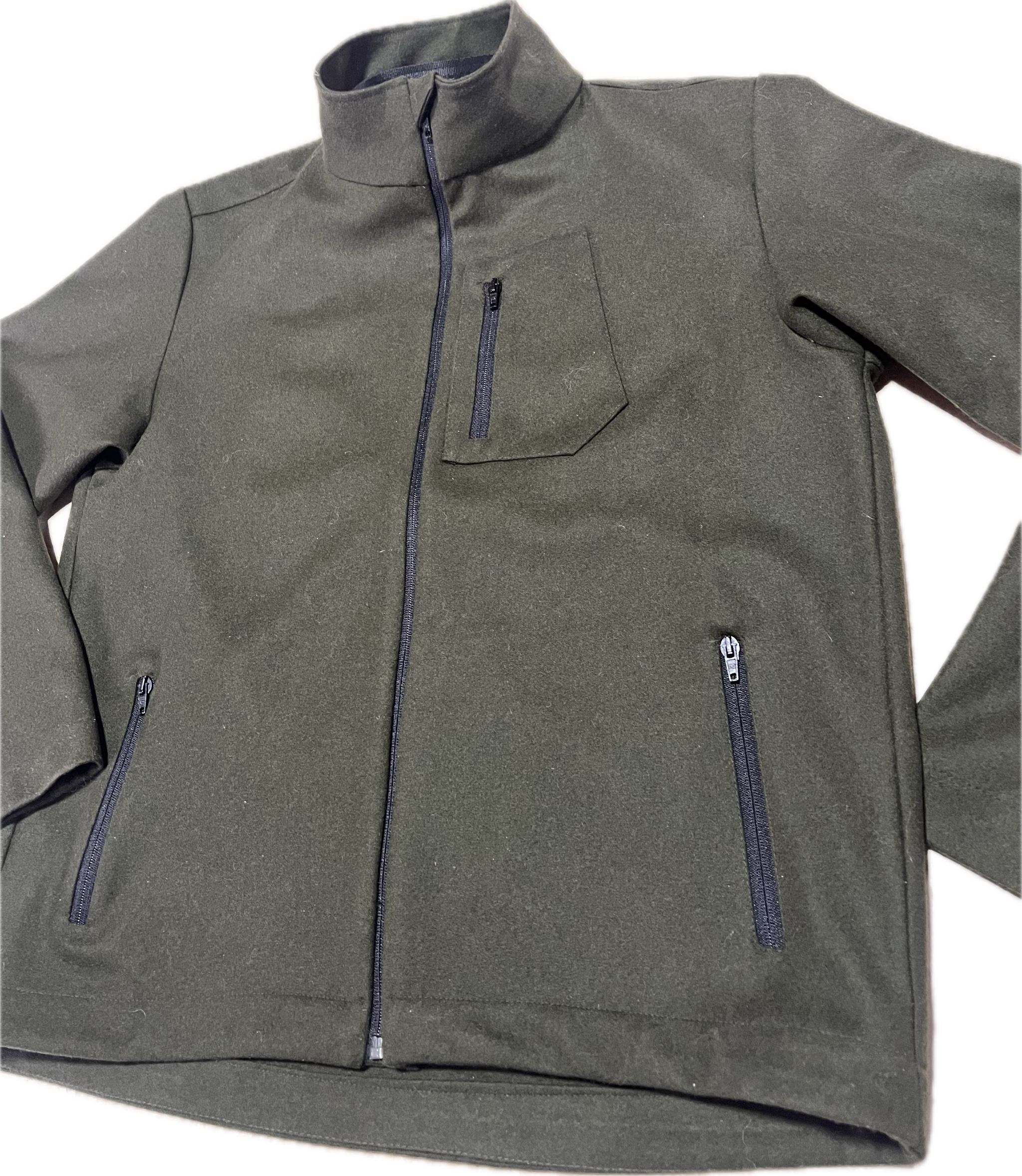 Roughstuff Leichtgaist leichte Lodenjacke für Alltag, Wandern und Outdoor-Aktivitäten. Dünne und angenehm zu tragende Jacke aus robuster Wollmischung mit sportlichem Schnitt, verstellbarem Bund und hoher Bewegungsfreiheit durch Rückenfalten. Ausgestattet mit seitlichen Taschen und Brusttasche, ideal als Zwischenschicht oder leichte Außenschicht bei mildem Wetter. Farbe Olivgrün