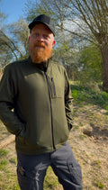 Roughstuff Leichtgaist leichte Lodenjacke für Alltag, Wandern und Outdoor-Aktivitäten. Dünne und angenehm zu tragende Jacke aus robuster Wollmischung mit sportlichem Schnitt, verstellbarem Bund und hoher Bewegungsfreiheit durch Rückenfalten. Ausgestattet mit seitlichen Taschen und Brusttasche, ideal als Zwischenschicht oder leichte Außenschicht bei mildem Wetter. Farbe Olivgrün