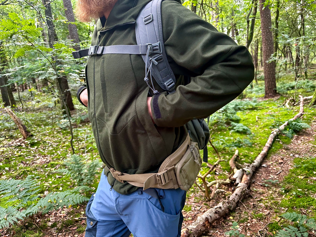 Roughstuff Bergteufel technische Lodenjacke für Outdoor, Trekking und Abenteuer bei jedem Wetter. Robuste Outdoorjacke mit sportlichem Schnitt, großer verstellbarer Kapuze, hohem Kragen und langen Belüftungsreißverschlüssen für optimalen Wind- und Wetterschutz. Ausgestattet mit großen Taschen, Raglanärmeln und funktionalen Details für maximale Bewegungsfreiheit beim Wandern, Radfahren und Bushcraft. Farbe Olivgrün Detail Tasche