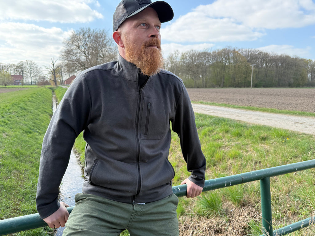 Roughstuff Leichtgaist leichte Lodenjacke für Alltag, Wandern und Outdoor-Aktivitäten. Dünne und angenehm zu tragende Jacke aus robuster Wollmischung mit sportlichem Schnitt, verstellbarem Bund und hoher Bewegungsfreiheit durch Rückenfalten. Ausgestattet mit seitlichen Taschen und Brusttasche, ideal als Zwischenschicht oder leichte Außenschicht bei mildem Wetter. Farbe Anthrazit